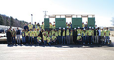 Photo of a group in matching t-shirts standing around a wall frame. Their shirts say "Self-Reliance."