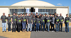 Photo of the Arizona State University and The University of New Mexico Solar Decathlon 2013 team standing in front of an airplane hangar. 