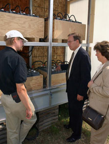 Photo of three people looking at batteries in the mechanical equipment room of the University of Colorado house.